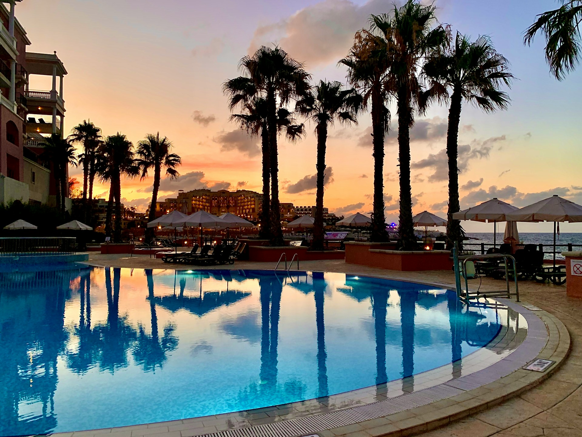 swimming pool inside a resort with a background of palm trees and sea